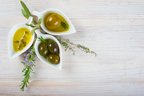 Extra virgin olive oil and green olives on a white wooden background with a copy space