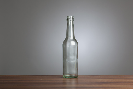 Three vintage glass bottles  including a soda pop bottle, a medicine bottle and a perfume bottle with reflections on a black background.