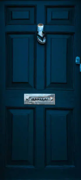 Photo of Blue door with brass knocker shaped flip-flops, metal letterbox, beautiful entrance to the house