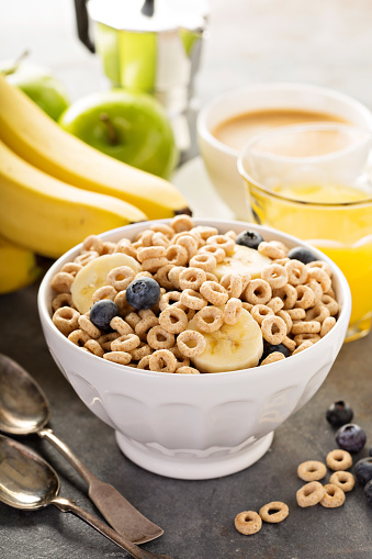 Healthy cold cereal with banana and blueberry in a white bowl, quick breakfast or snack for children