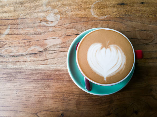 istock A red cup of coffee with heart pattern on wooden background 673754102