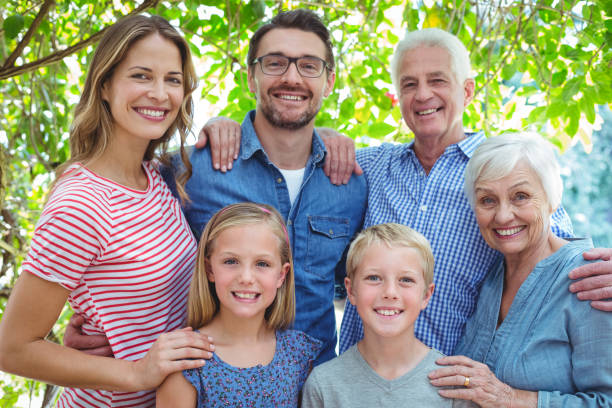 istock Smiling family standing against tree 673758396
