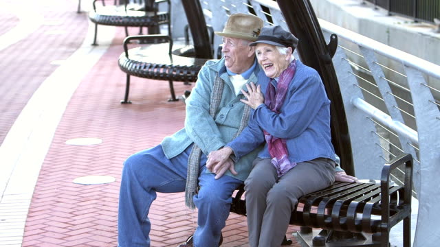 Senior couple sitting on bench, talking, enjoying view