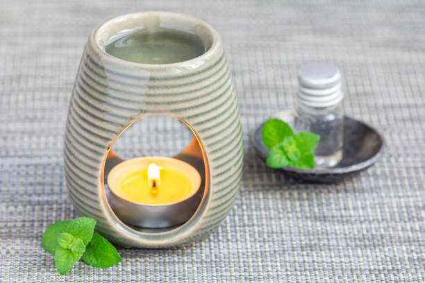 istock Peppermint essential oil in aroma lamp on gray mat with spa background, horizontal 673765994