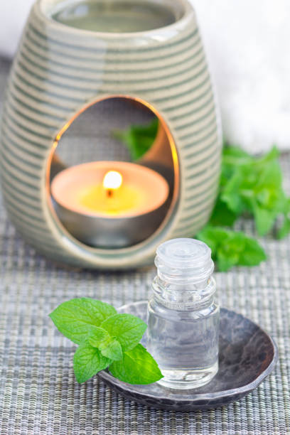 istock Peppermint essential oil in glass on gray mat with spa background, vertical 673766014