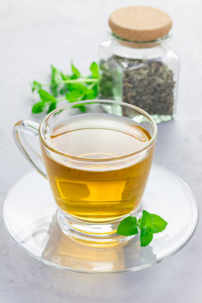 istock Herbal mint tea in a glass cup with dry peppermint tea on background, vertical 673766042