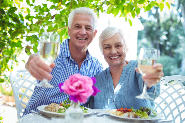 istock smiling senior couple offering white wine 673768926