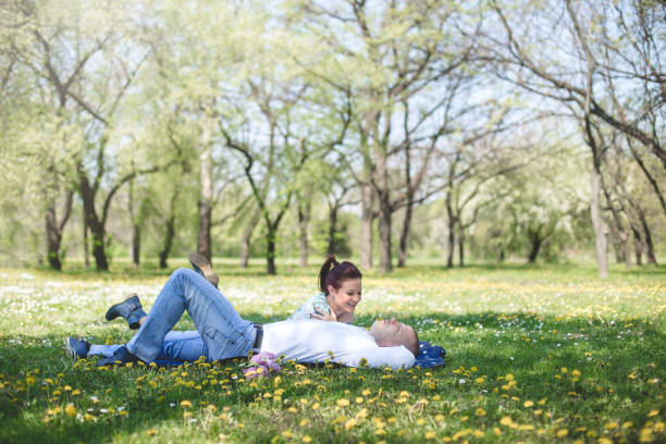 A couple is lying on a grass in spring and enjoying their love.