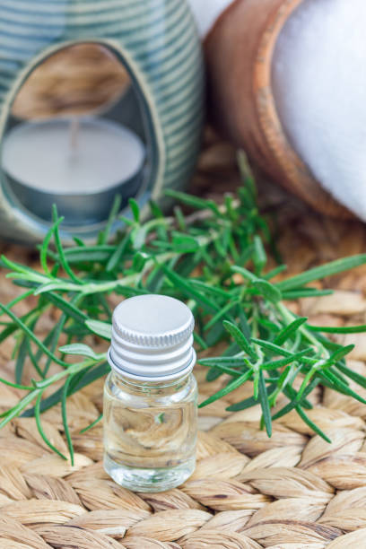 istock Rosemary essential oil in glass on woven mat with spa background, vertical 673777352