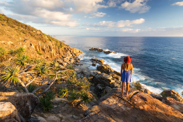 Girl and Coastal View A young woman admires a coastal view at sunrise near Coffs Harbour, Australia. coffs harbour stock pictures, royalty-free photos & images
