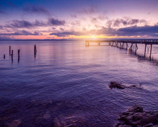 istock Wooden pier extending toward the setting sun 673780074