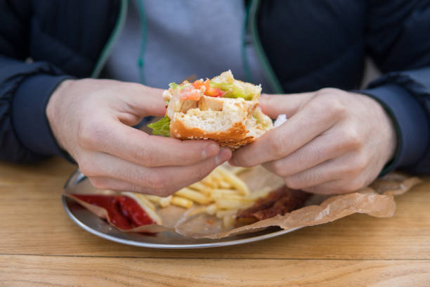 istock Men's hands hold a piece of bitten burger. 673788652