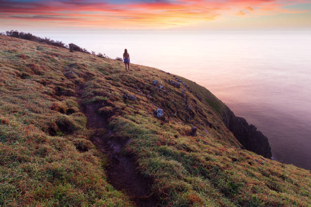 istock Girl silhouetted at sunrise on a Coastal Trail 673789574