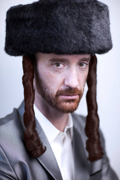 retrato de un joven judío hasdim ortodoxo con barba roja y sombrero de piel negro en un traje de negocios plateado - east european jewish fotografías e imágenes de stock