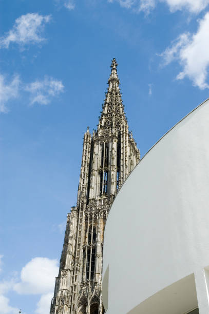 Ulm Minster View of the main tower of Ulm Minster along the façade of the Stadthaus ulm minster stock pictures, royalty-free photos & images