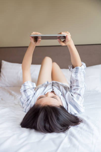 istock young woman lying on home bed using digital tablet 673808106