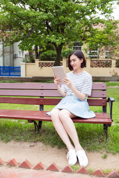 istock Beautiful girl sitting on a bench and using digital tablet 673812036