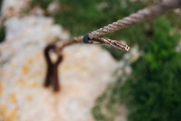 istock Rusty metal cable tied to a metal loop in the ground closeup blurred. 673812222