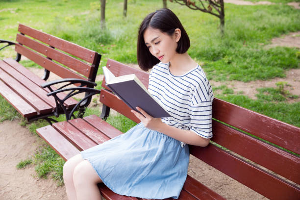 istock Beautiful girl sitting on a bench and reading a book 673812318