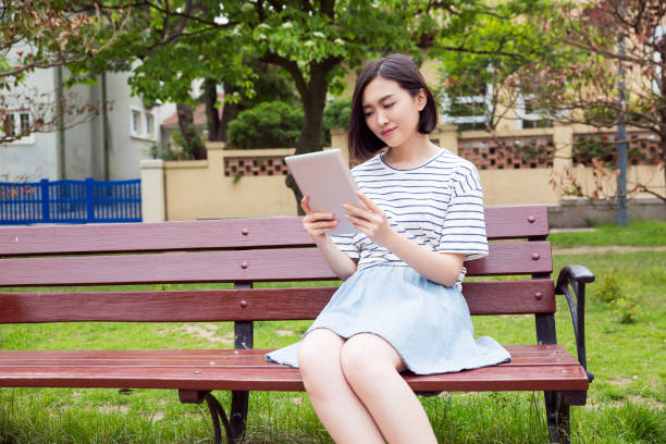 istock Beautiful girl sitting on a bench and using digital tablet 673812576