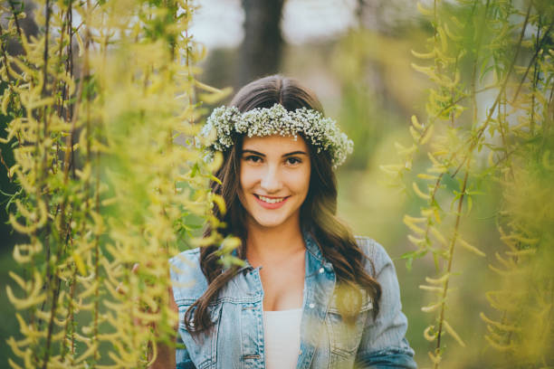 Young beautiful woman posing with flower crown on her head during spring day.