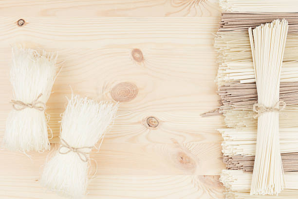 Bundles of raw chinece noodles  on soft beige wooden board with copy space, top view.