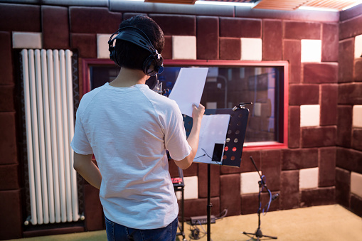 Close up of a young singer recording a track in a studio.