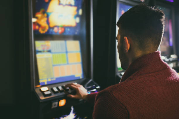 istock Man playing a slot machine in a casino. 673833716