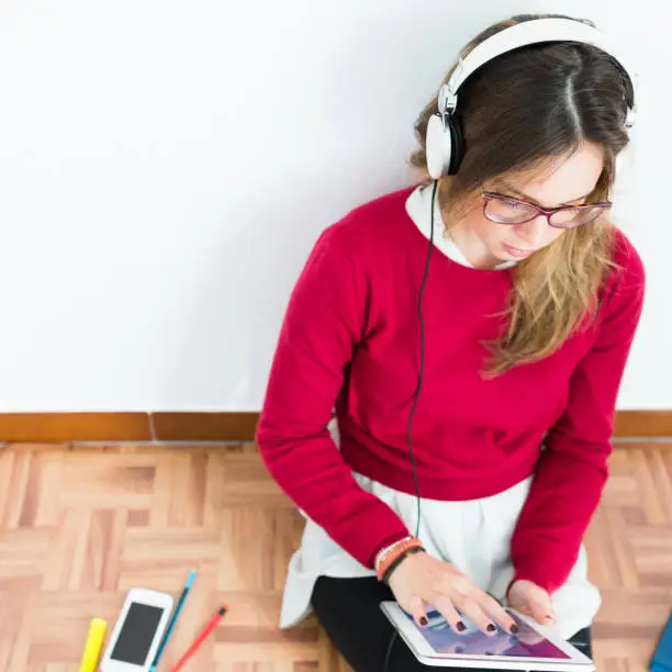 Photo of Young woman listens and learns with digital tablet