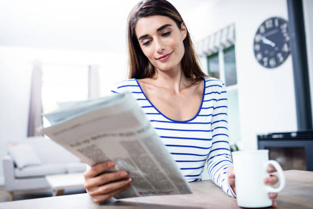 istock Woman reading newspaper while holding mug 673847410