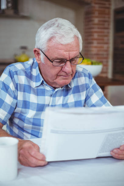istock Senior man reading newspaper in kitchen 673850534
