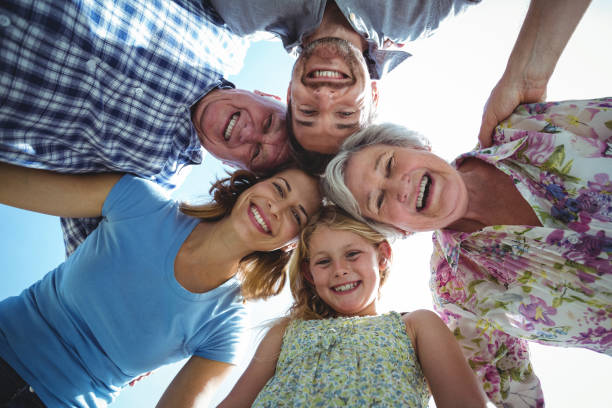 istock Cheerful family forming huddle against sky 673854360
