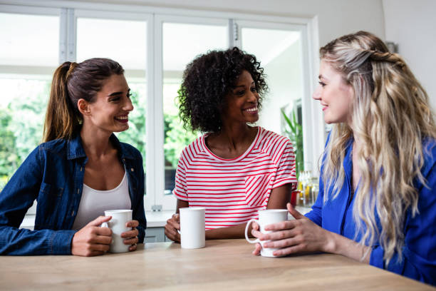 istock Female friends with coffee mug sitting at table 673861880