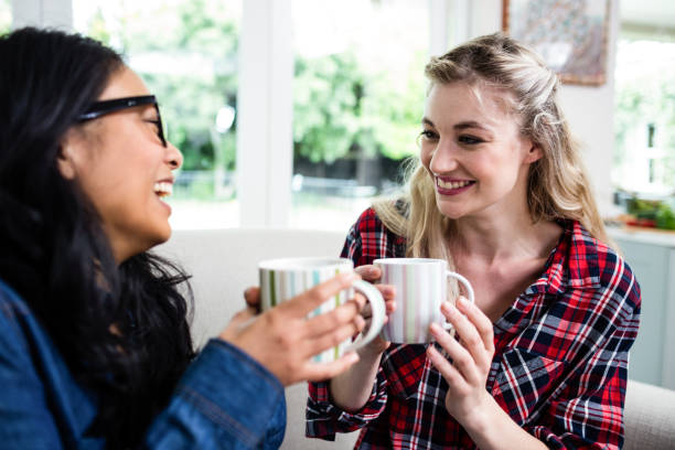 istock Cheerful female friends drinking coffee at home 673865596