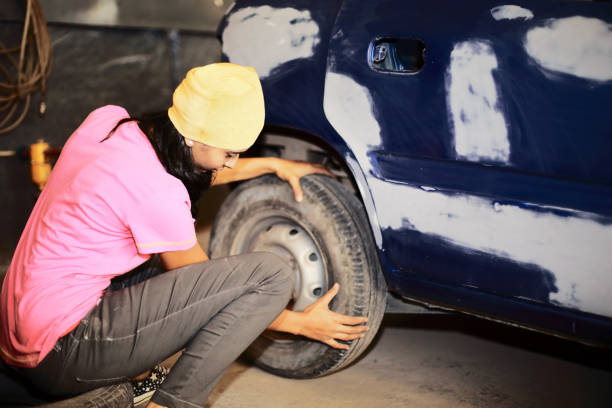 Young female mechanic fitting the car wheel in an auto garage.