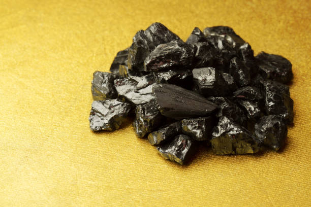istock Raw coal nuggets on golden textured background 673869174