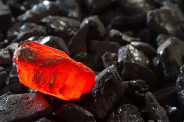 Photo of Red hot coal on raw coal background