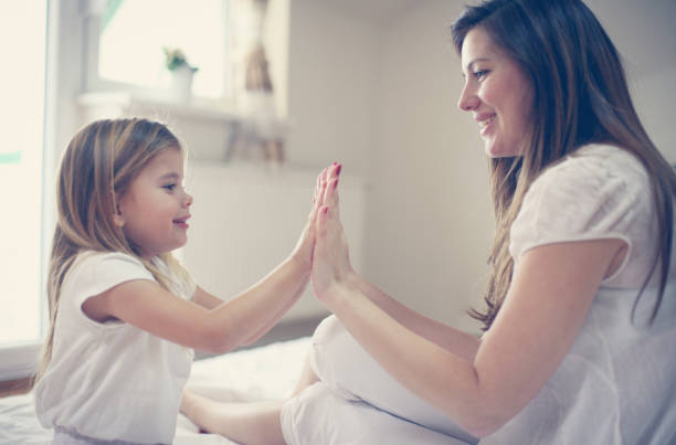 istock Mother with her cute little daughter sitting on bed. 673886414
