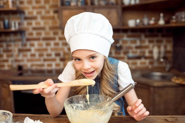 istock little girl in chef hat making dough for cookies 673890984