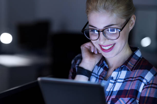 istock Amused IT girl using gadget in the dark lighted room 673892524