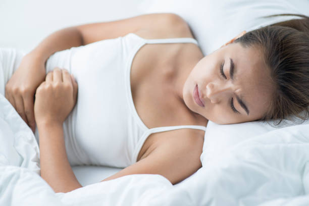 istock woman lying on the bad having stomach ache 673897618