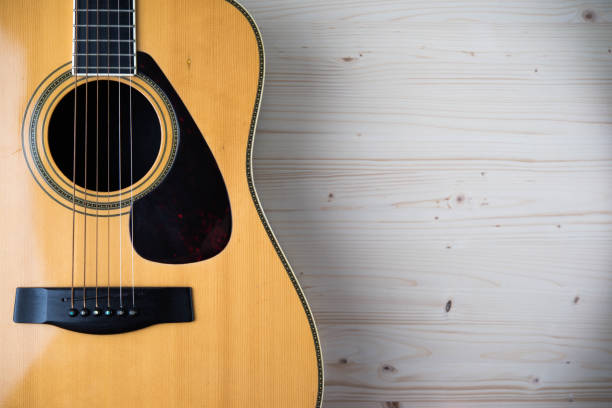 istock Acoustic guitar resting against a wooden background with copy space 673897700