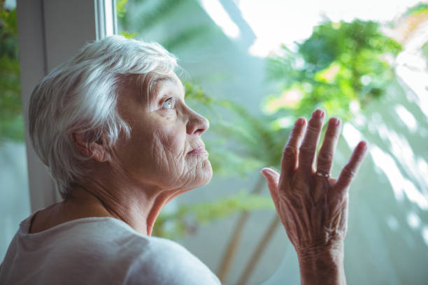 istock Senior woman looking through house window 673909488