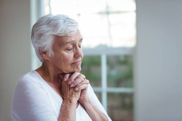 istock Senior woman praying at home 673909604