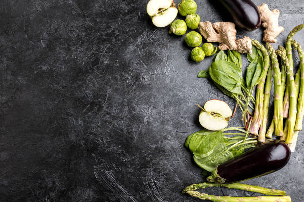 different green fresh seasonal vegetables on black table top background with copy space