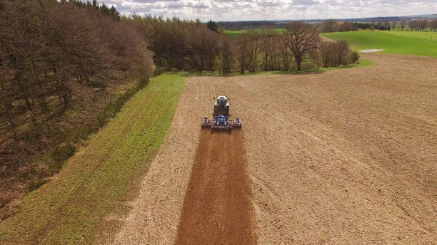 istock Aerial view of beautiful agricultural fields in spring with a tractor at work - cultivating a field 673914814