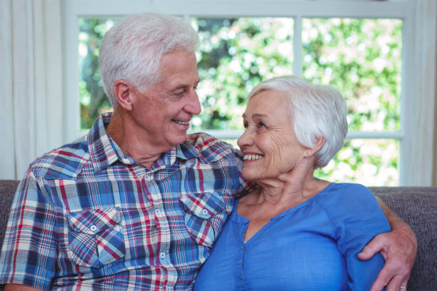 istock Senior couple looking at each other while sitting on sofa 673915064