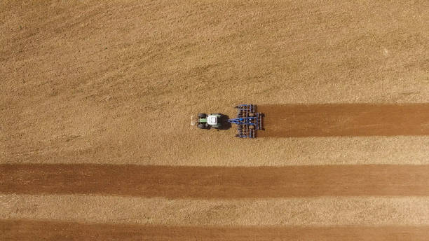 aerial view of a tractor at work on a beautiful agricultural fields in spring - top view stock photo