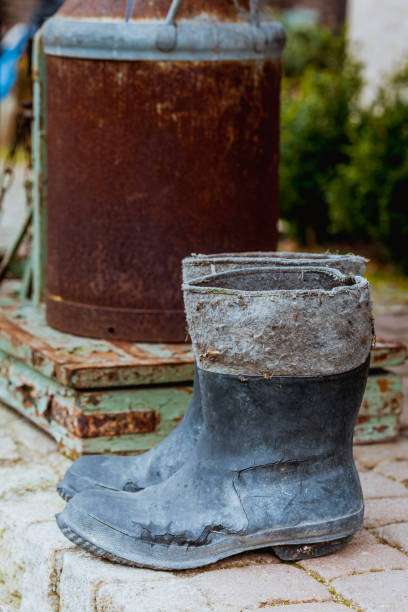 istock Very old wellingtons and copper bottle standing outside 673925644