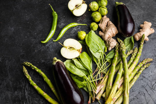 istock different green fresh seasonal vegetables on black table top background 673926258